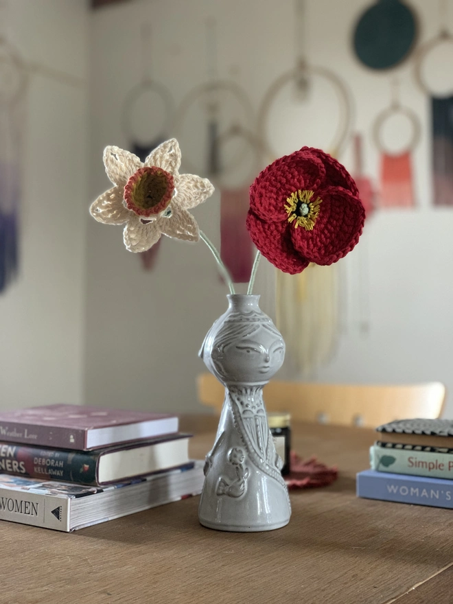 crocheted poppy and daffodil in vase on table
