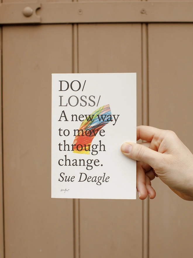 Paperback book held up against painted brown door