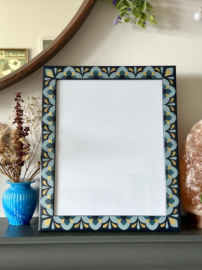 Heavily patterned medium sized picture frame hand painted in shades of blue with gold details