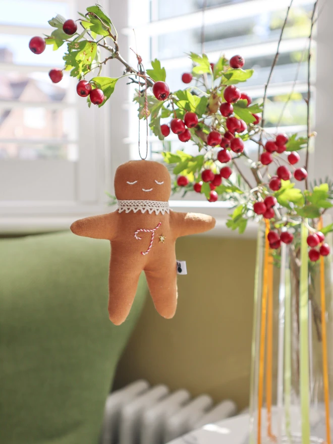 Brown linen gingerbread man christmas tree ornament with a letter hand embroidered in candy cane colours, star shaped sequin, crochet cotton lace around the neck, smile embroidered in white and candy cane colour string to hang. 