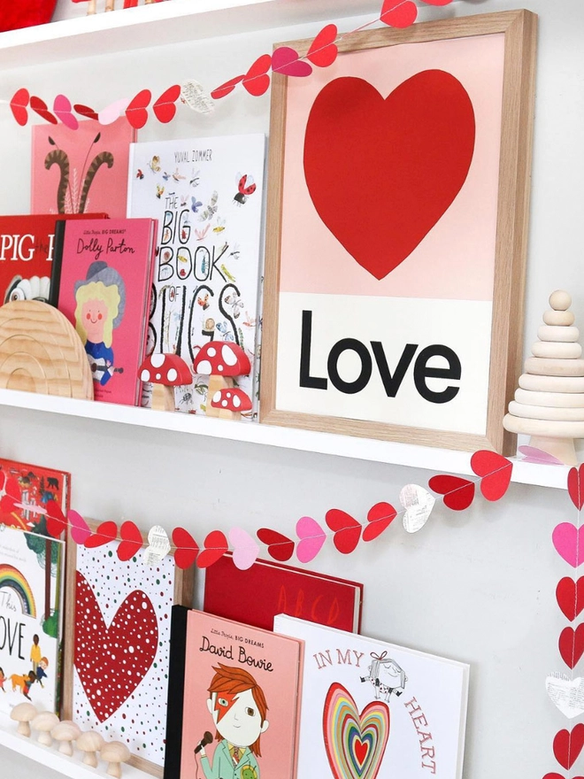 framed illustrated love heart wall print with the word Love at the bottom propped on book shelf