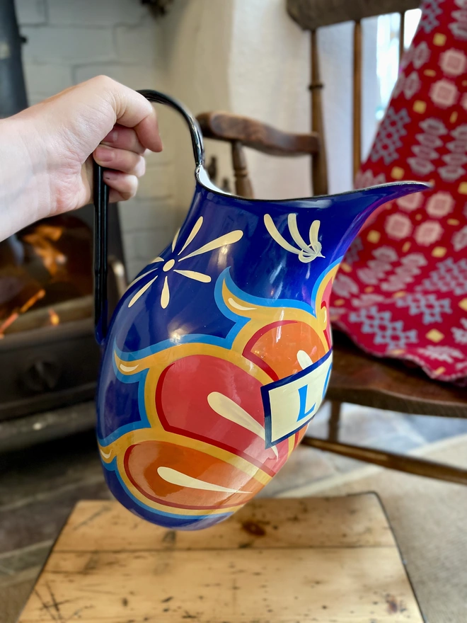 Vintage blue enamel jug hand painted with a fairground inspired design in pink, orange, yellow and red.