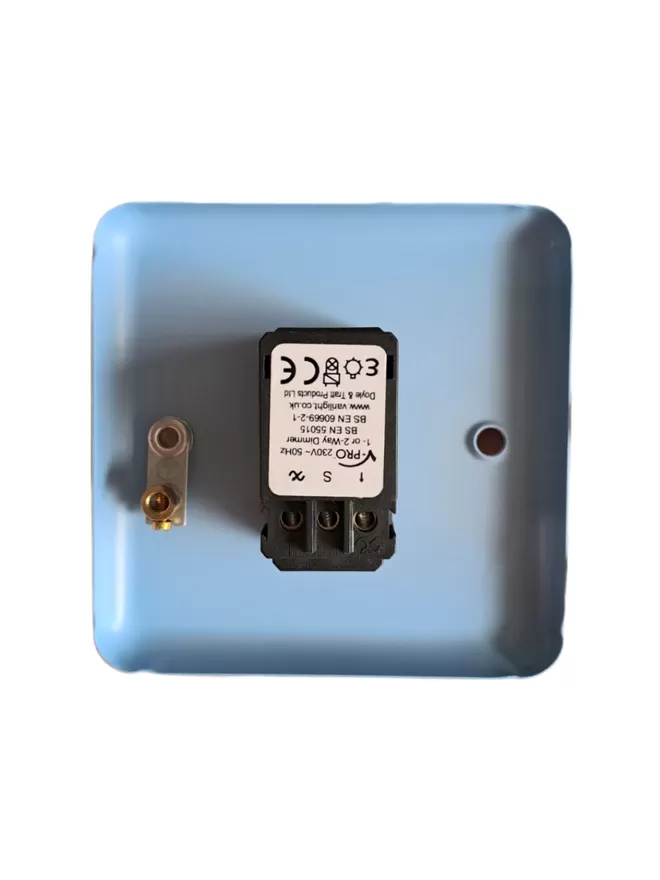 The back of a blue steel metal epoxy coated light switch plate, there is a black rectangle LED dimmer switch module in the centre of the switch plate, the module has three round holes at it’s base for wires and a white label with V Pro, 230v – 50Hz 1 or 2 way Dimmer, BS EN 55015, BS EN 60669 – 2- 1 www.varilight.co.uk, Doyle & Tratt products Ltd written one it, there are two screw holes in the light switch, the hole on the left also has an earthing screw on it.