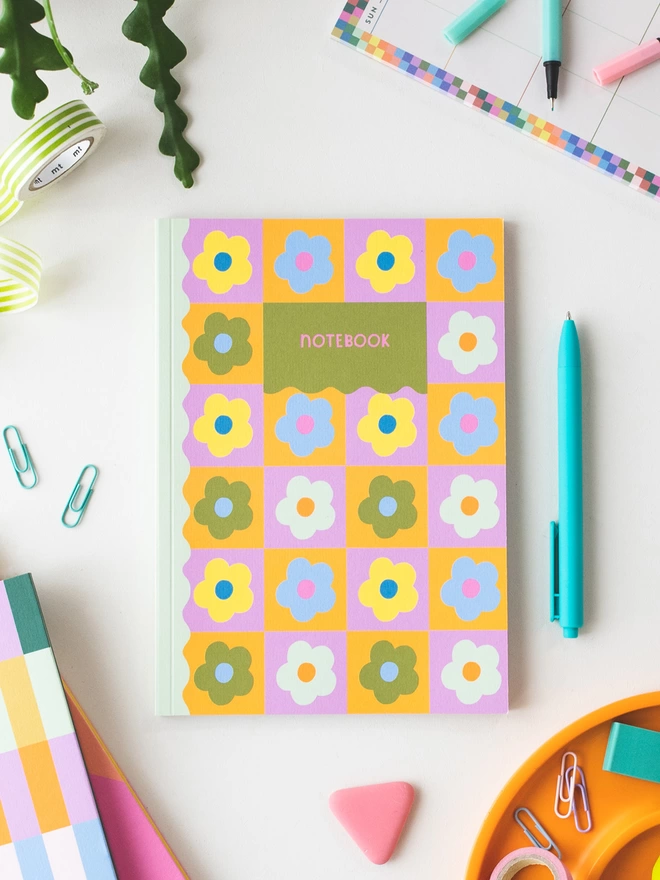 A5 pink and orange check floral notebook sits on desk