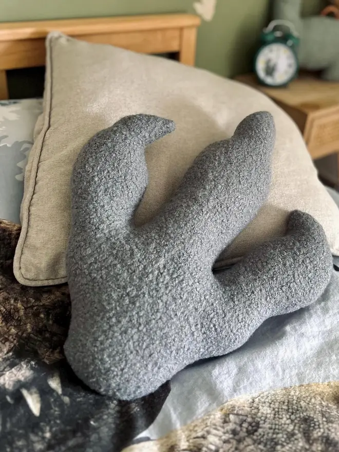 boucle dinosaur footprint cushion. a grey dinosaur foot cushion.