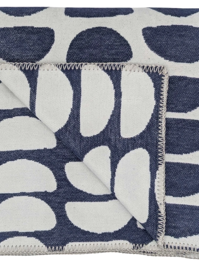Organic Cotton Throw, a cotton throw folded into a square on a floor. 