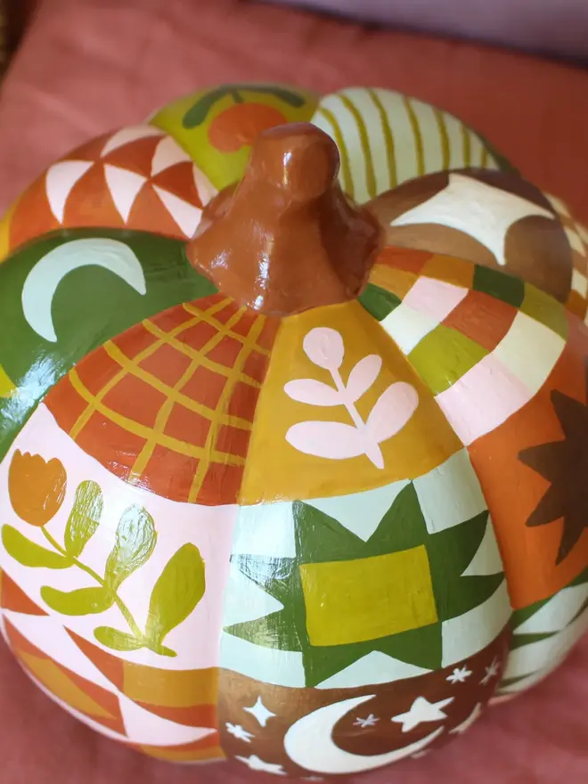 hand-painted woodland ceramic pumpkin. a ceramic pumpkin painted with patchwork colours and patters, alongside mushrooms, moons, stars and flowers.