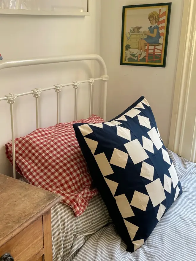 Astrid Patchwork Cushion, on a bed. 