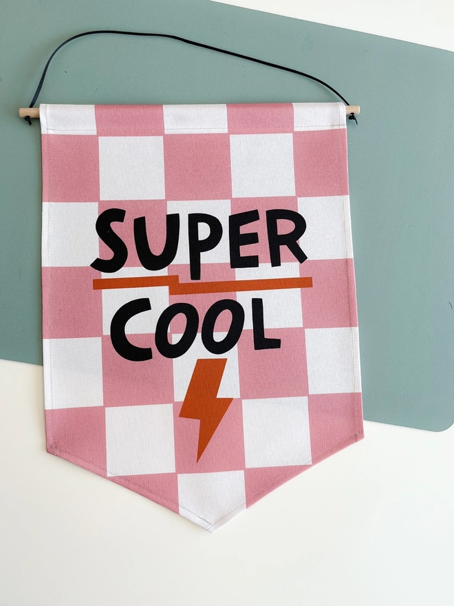 Pink and white chequered wall banner with the words super cool