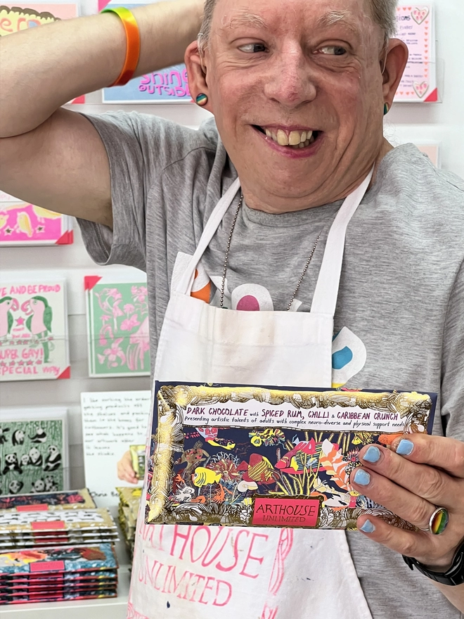 Artist holding charity dark chocolate bar packaged in foiled card & colourful fish illustrations