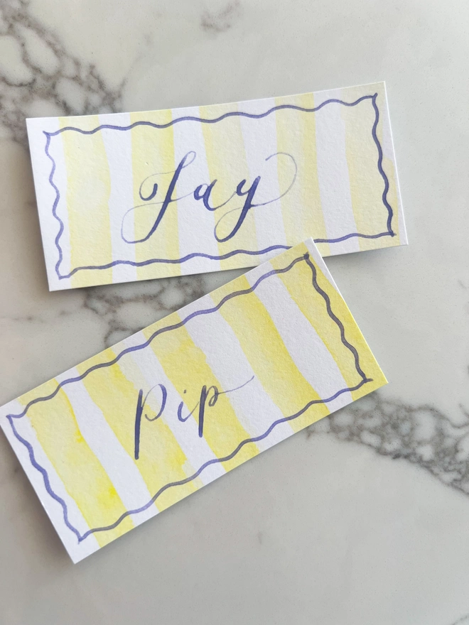 Personalised calligraphy event place cards, yellow striped coloured place cards with wisteria calligraphy name
