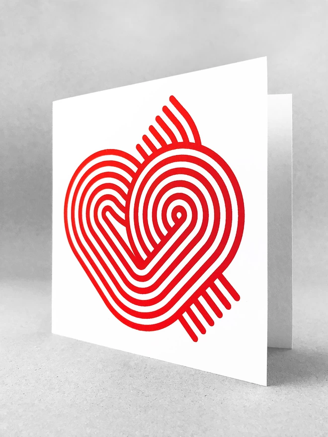 Six magenta swirling stripes create a neat heart-like graphic on the front of this square white card. This studio shot shows the card slightly open on a light grey background.