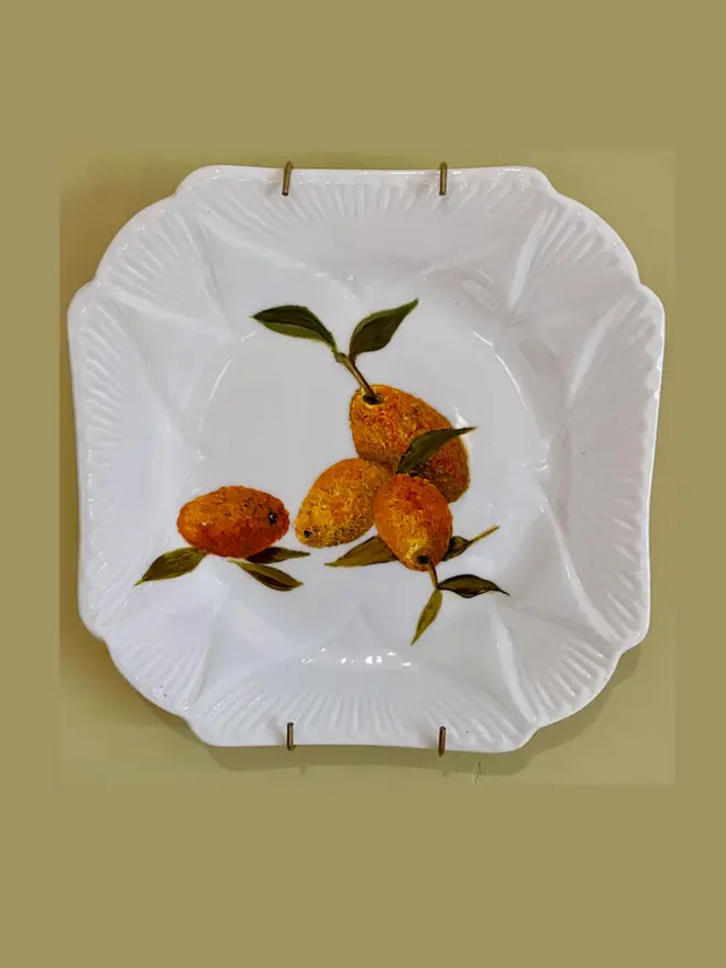 Fine Art Oil Painted Kumquats On A Antique Tea Plate, hanging on a yellow wall. 