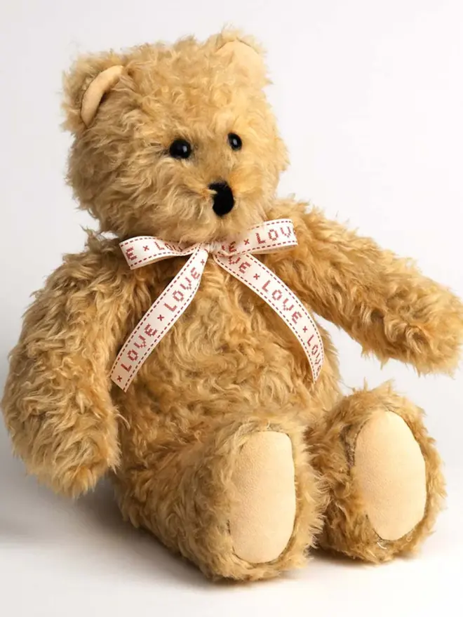 golden brown teddy bear with pale bow that reads 'love'