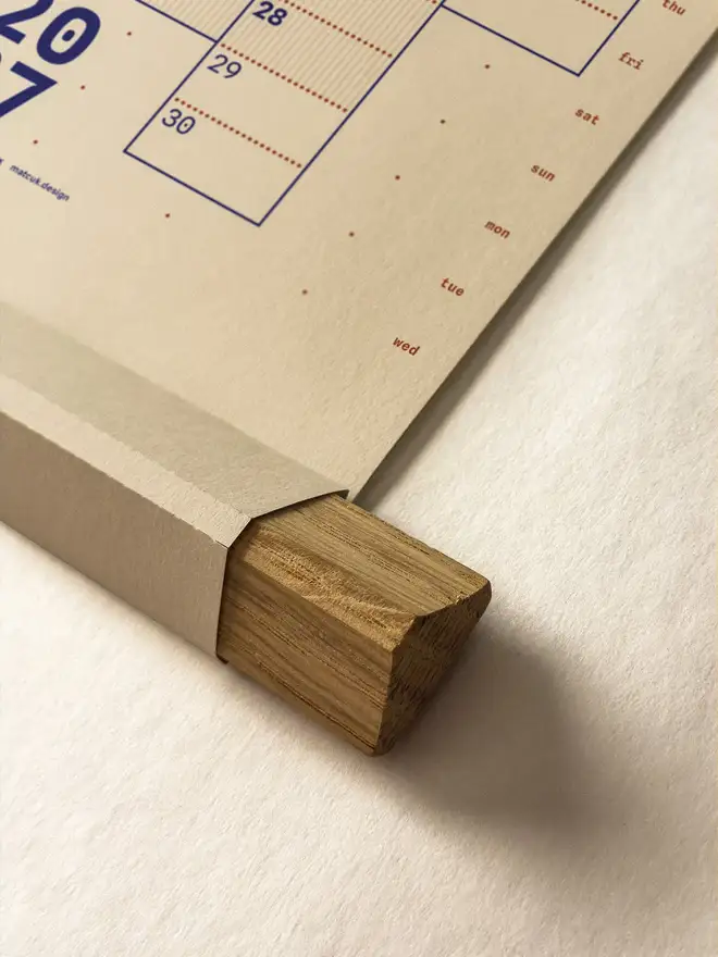 Closeup of oak hanger frame of a neutral 'clay' Dotline 2027 yearly wall planner on a neutral background