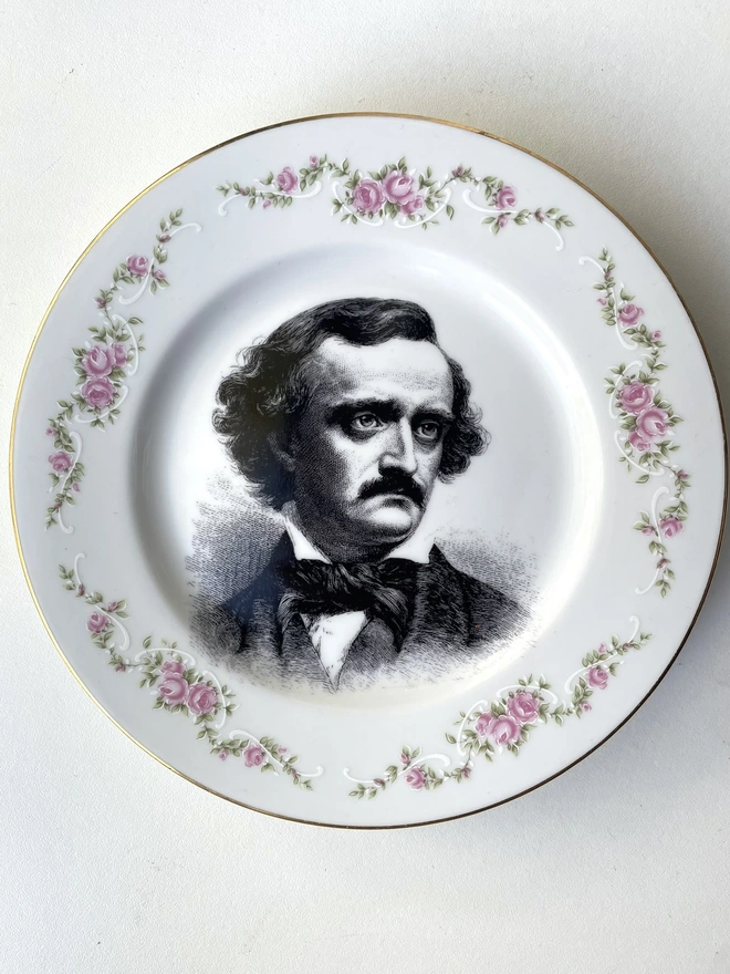 vintage plate with an ornate border, with a printed vintage illustration of Edgar Allen Poe in the middle 