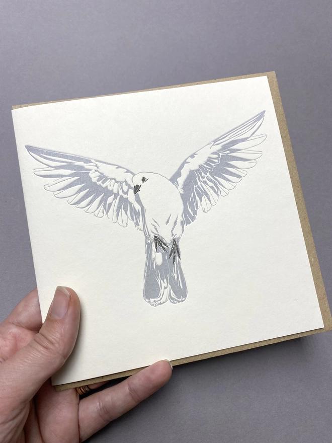 A hand holding the dove card 