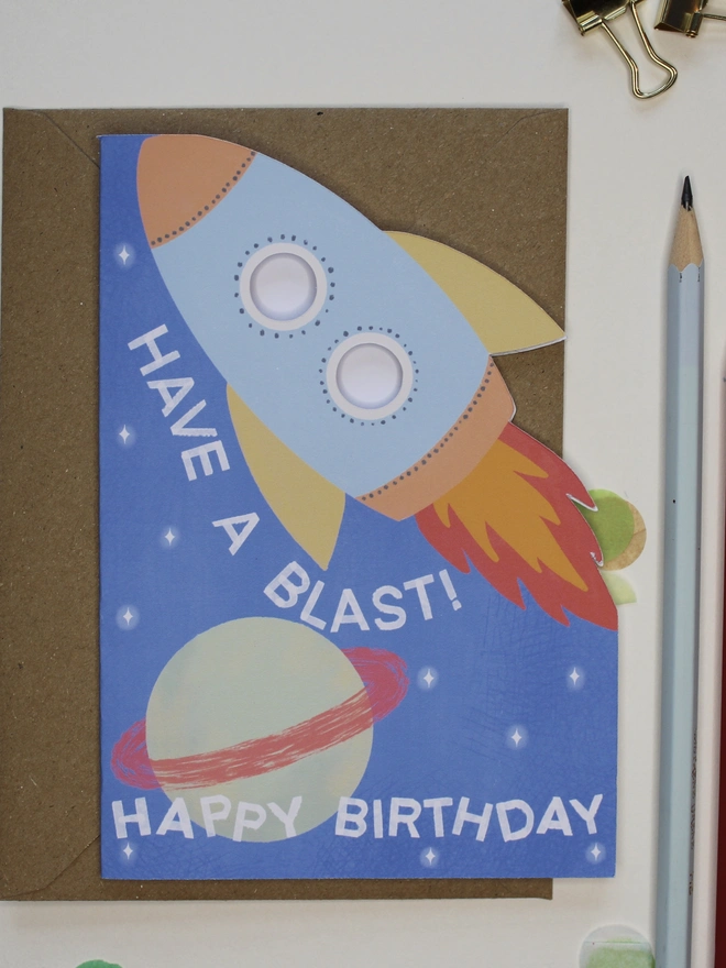 have a blast rocket birthday card. blue card with illustrated rocket and planets.
