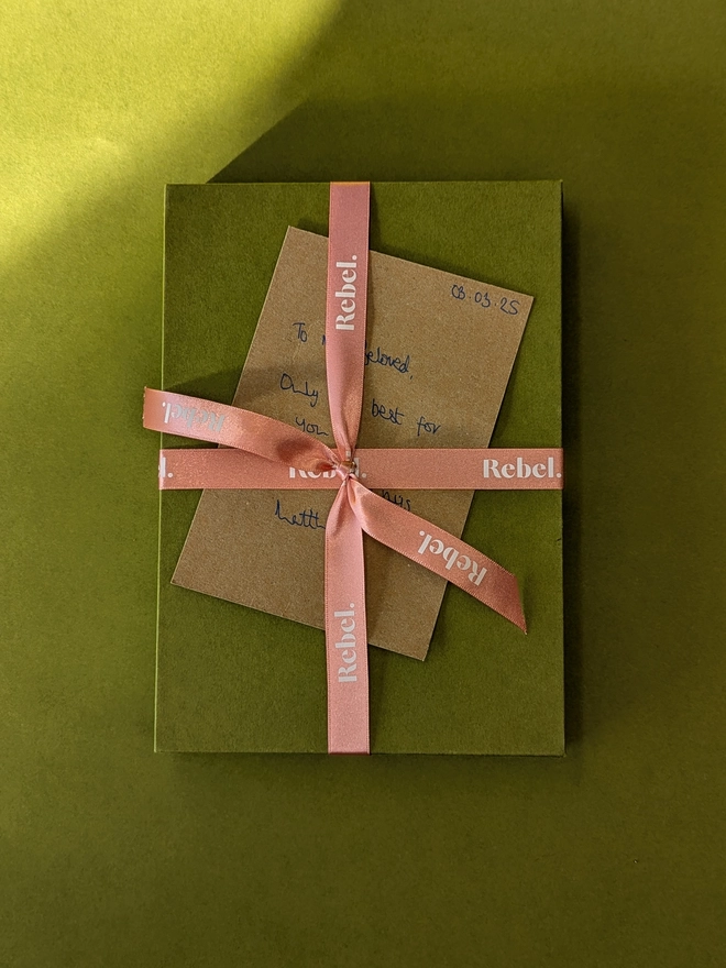 Rebel Stationery's gift wrapped green slipcase with pink branded ribbon and handwritten note on recycled brown Kraft A6 card