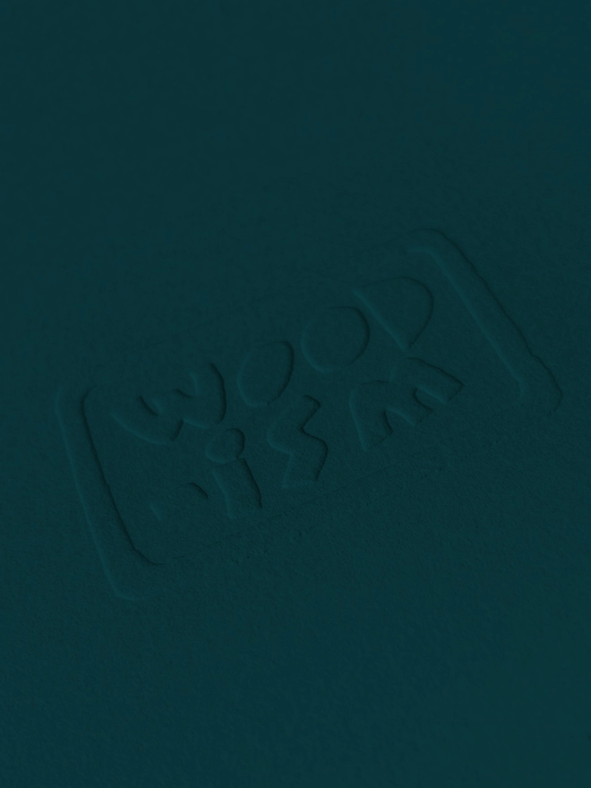 The embossed Woodism logo on green paper 