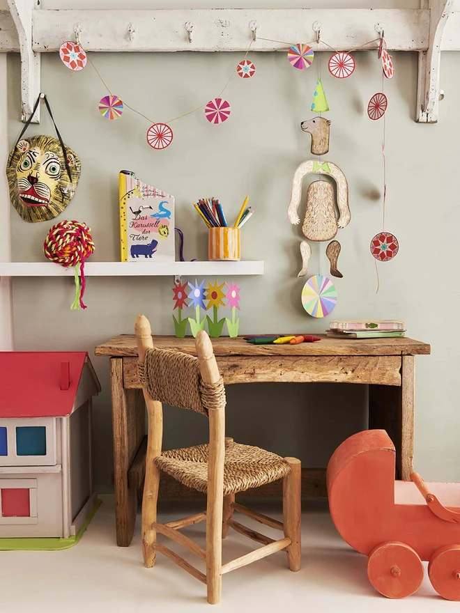 Lifestyle image of a polar bear mobile dancing on a ball, hanging over a cute kids desk and next to some wooden vintage toys