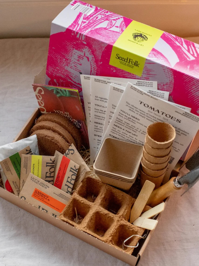 the seed growing starter kit. box in a decorative pink sleeve photographed alongside gardening supplies inside.