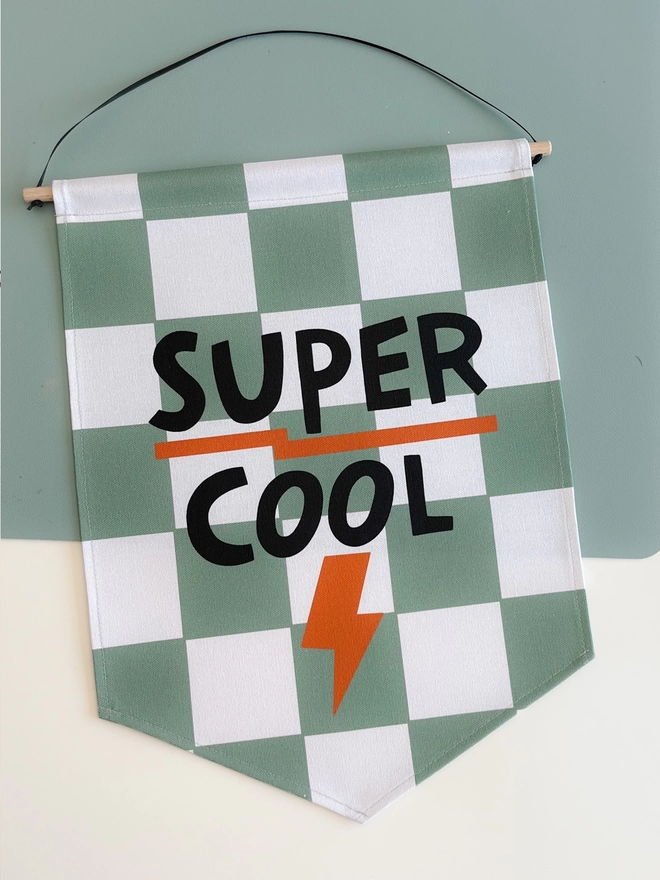 Green and white chequered wall banner with black lettering saying super cool