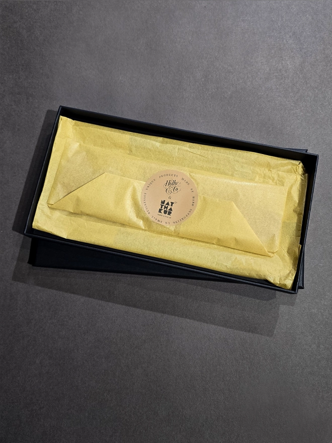 a leather lancaster bomber airplane bookmark wrapped in yellow tissue paper and packaged in a black gift box