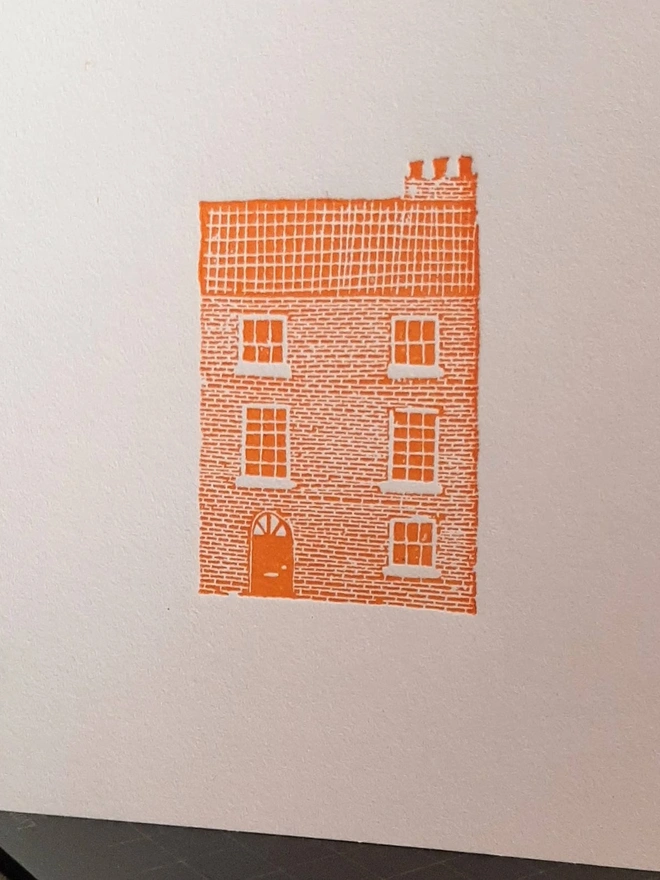 Orange Townhouse Letterpress Handprinted Greetings Card, a white card with an orange townhouse design in the centre. 