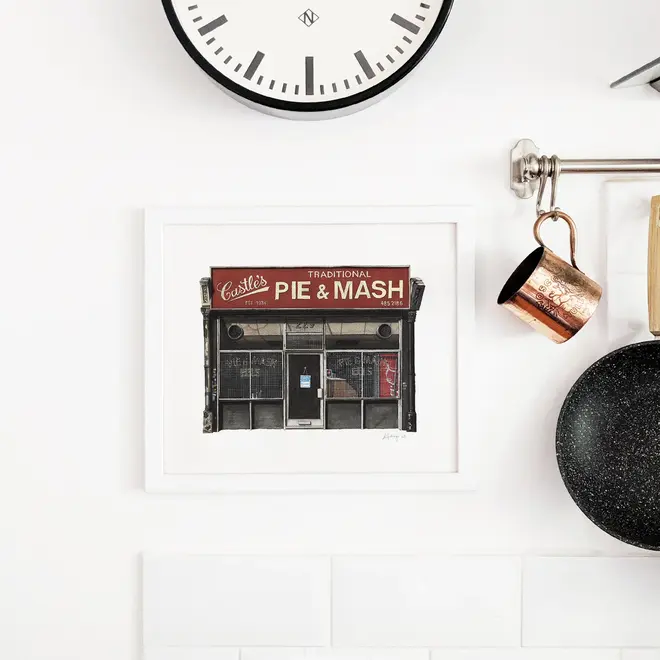 Camden Castle's Pie & Mash Shop Giclée Print (Unframed), a print of a shop sitting against a white backdrop. It is accompanied by a clock. 