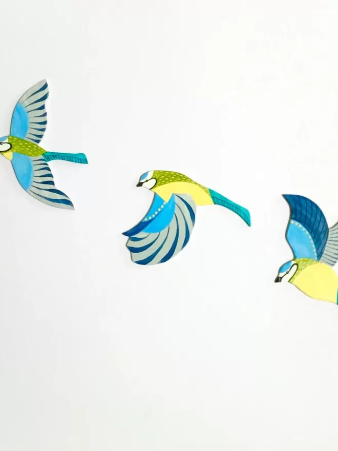 3 blue tits arranged on a white wall