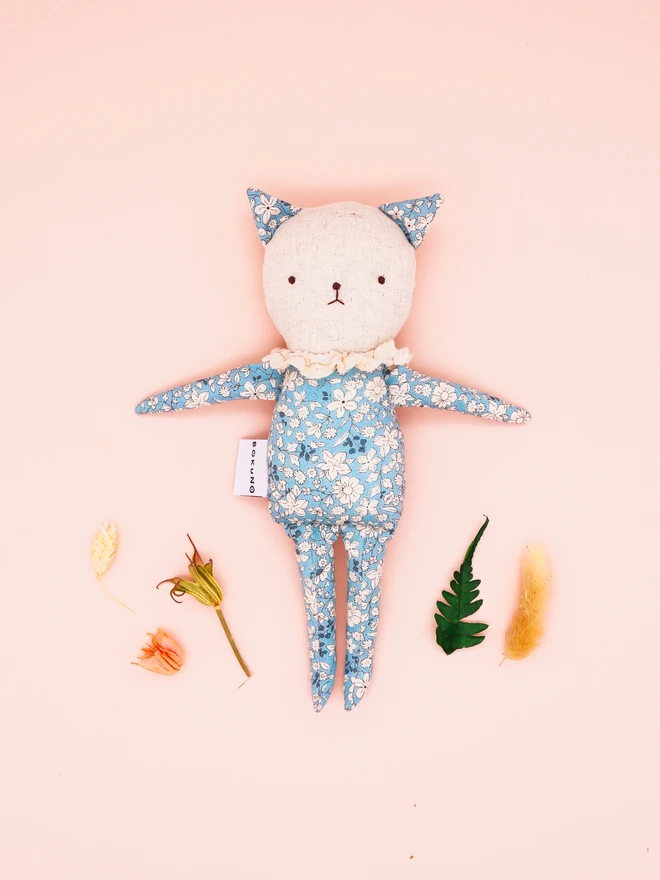 A handmade fabric doll in pastel floral prints, designed with distinct cat features. This doll has a linen face, simple embroidered features, and delicate ruffled collars, showcasing their artisan craftsmanship.