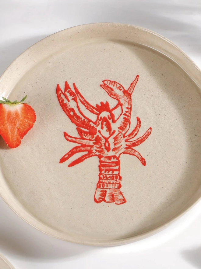 Handmade Ceramic Side Plate With Red Lobster Design, a side plate with a red lobster design on a white table. 