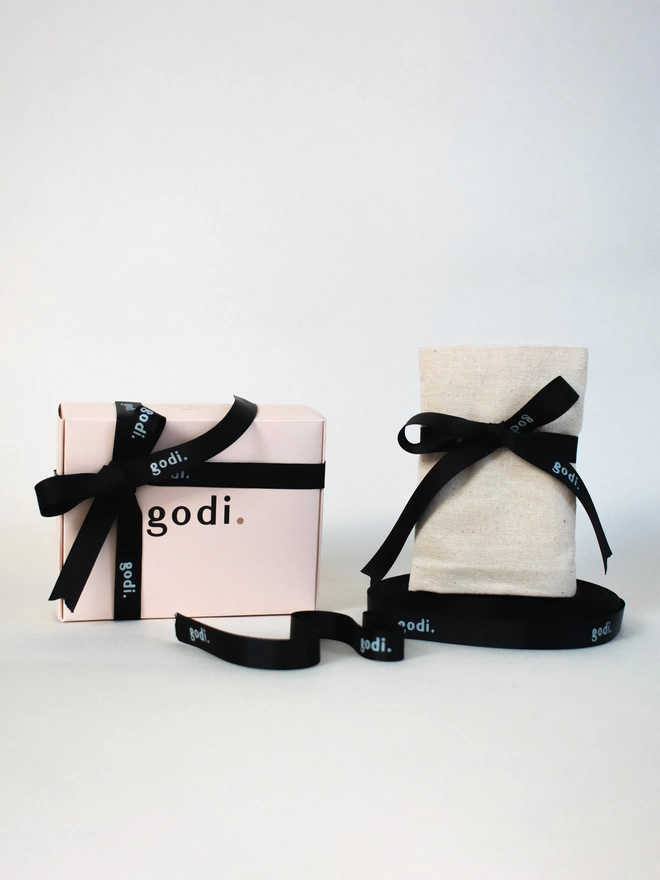 Photo of gift wrapping with a box with a ribbon tied on the left and an organic cotton bag with a godi. ribbon on the right of the photo.