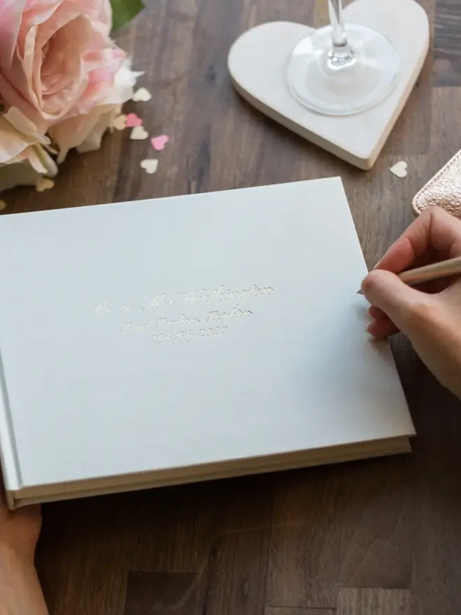 Personalised Calligraphy Font Wedding Guest Book, about to be written in on a wooden surface. 