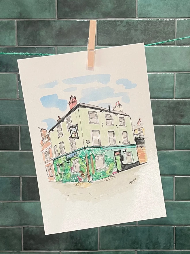watercolour painting of a Pub, hanging from a clothesline in front of green tile