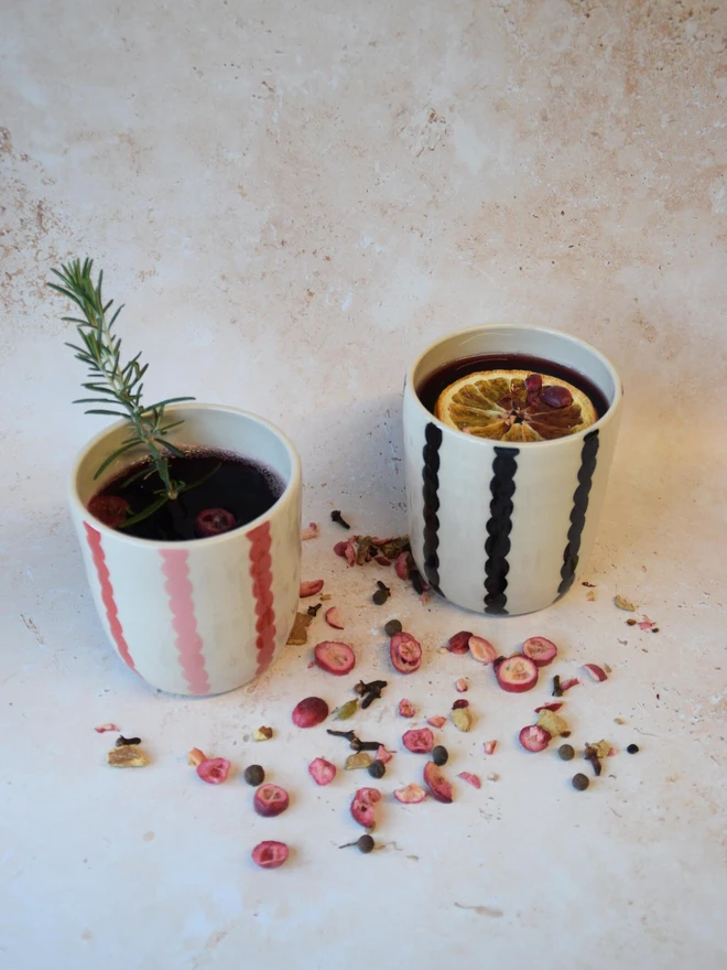 Handmade ceramic Stripe Pop tumblers - red and black colourways styled with drinks and herbs