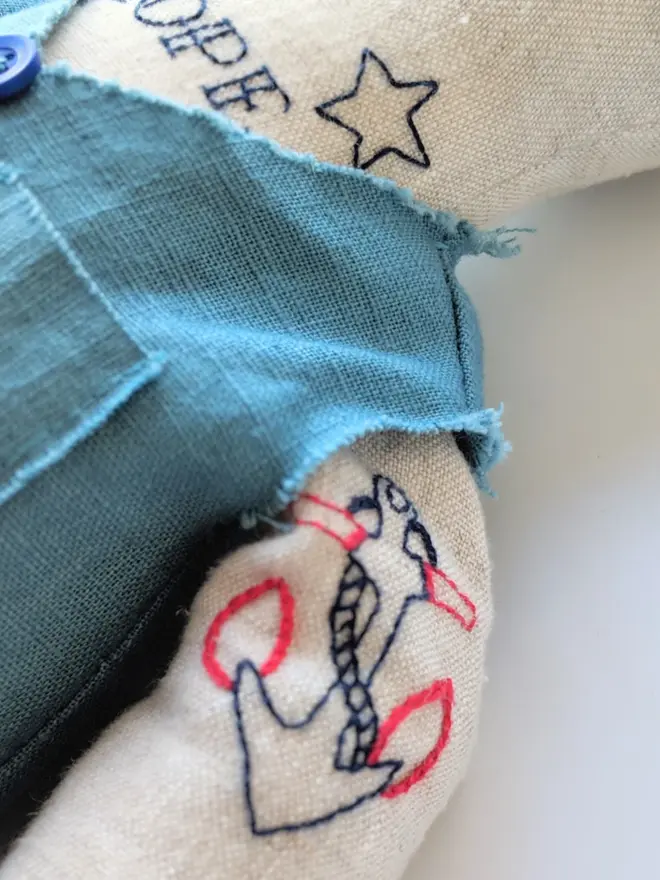 tattooed bear doll. a cream linen bear doll with embroidered arm tattoos and a blue waistcoat.