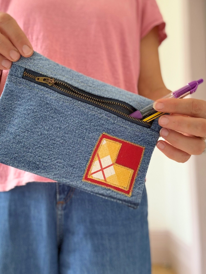 Handmade pencil case made from reclaimed denim with a zip fastening and a bright vintage‑print initial on the front