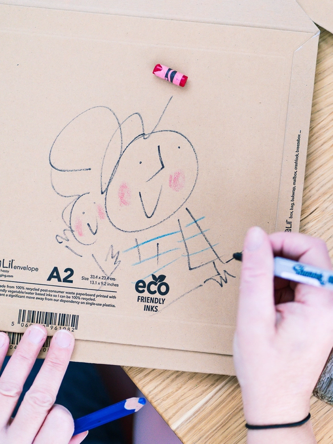 Hands drawing a sketchy muma picture on a brown envelope.