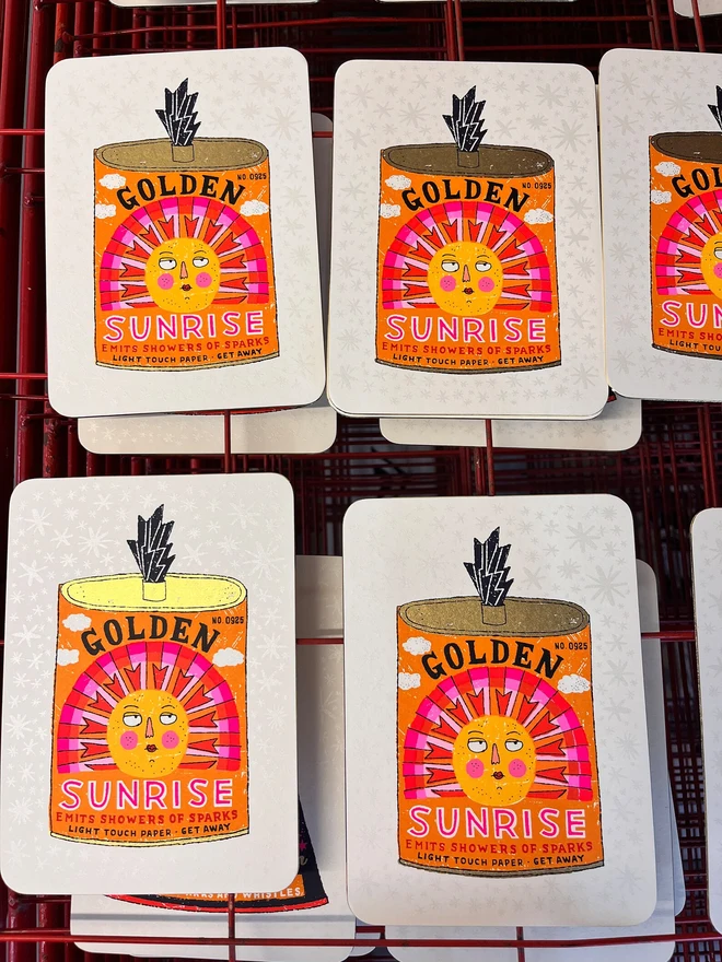 Bright Spark Sun Firework Screenprint, a colourful firework tin design on a white screenprint sitting on a studio rack. 