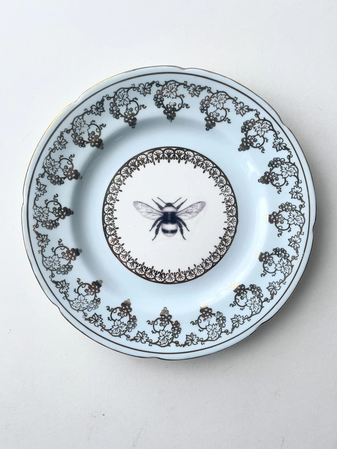 a vintage plate with a really decorate powder blue and gold patterned border, in the white centre i have printed a vintage black and white illustration of a bee