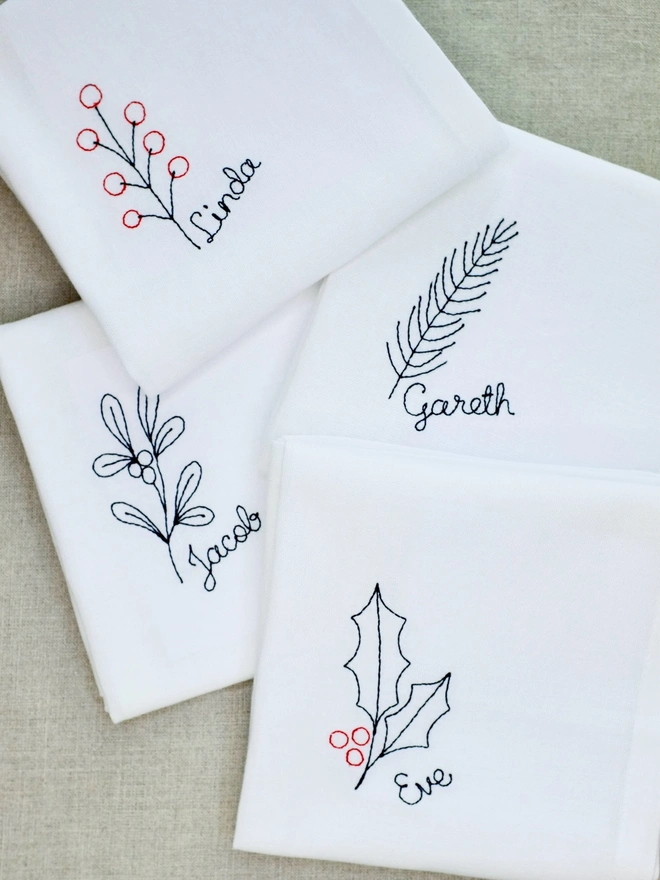 Set of four botanical Christmas personalised name embroidered napkins with berry, fir, mistletoe, and holly
