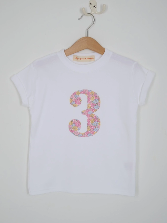 a white birthday t-shirt with a number 3 cut from liberty floral print on the front