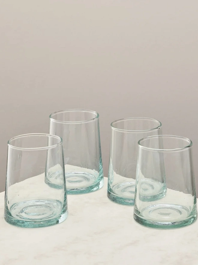 Tumbler Glasses (Set Of 1 Or 4), a set of tumbler glasses sitting on a plain counter top against a white backdrop. 
