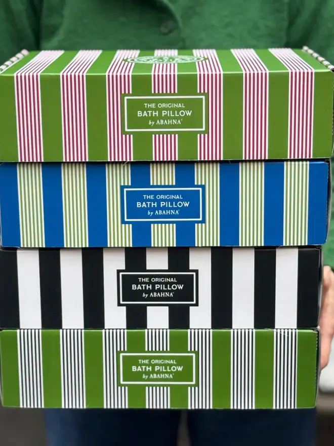 luxury frilled bath pillow. four boxes in different coloured stripes stacked on top of each other.