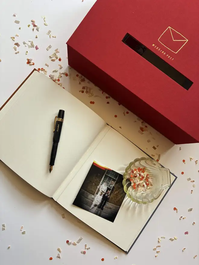 Confetti littered table with handmade wedding postbox by Keep Collect and open instant photograph guestbook