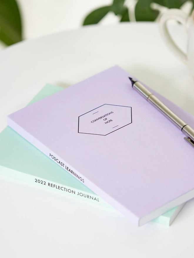 two colourful notebooks with personalised text down the spine