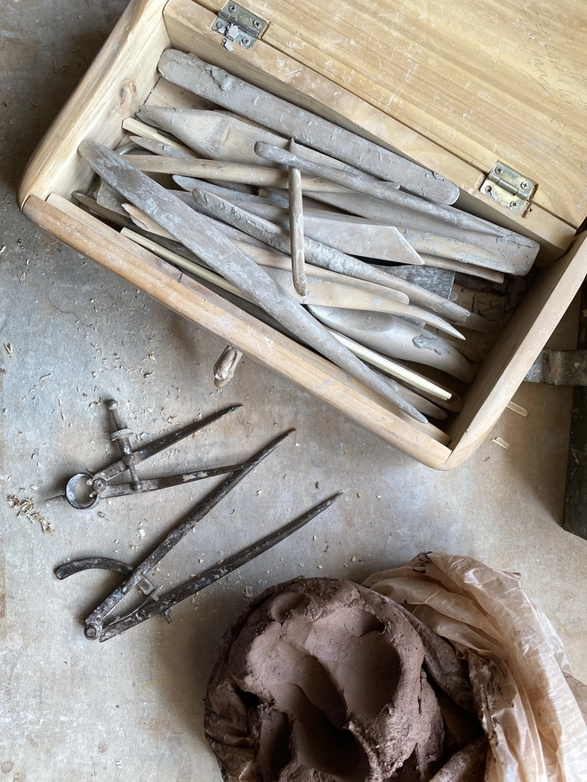 Modelling tools in a wooden box with clay and measuring dividers