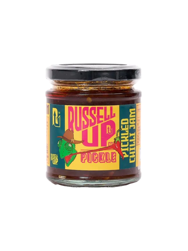 pickled sweet chilli jam. a jar of pickled chilli jam photographed against a white background, with a chameleon eating a chilli on the label. 